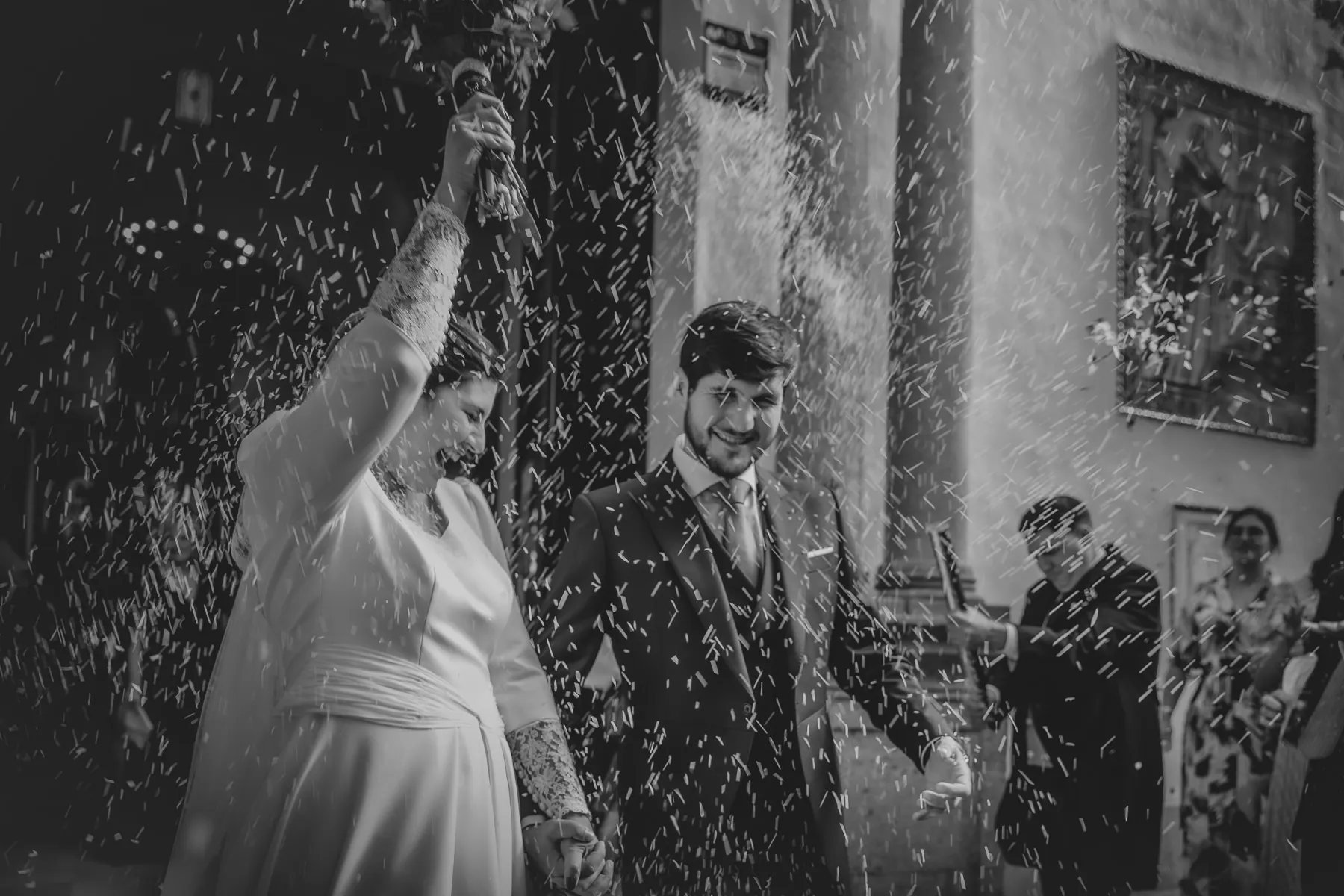 Imagen blanco y negro de los reciéb casados y  la salida de la iglesia fue un estallido de felicidad, marcado por el tradicional rito del arroz. ©Foto Alba 2022