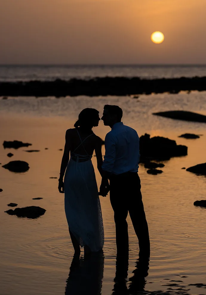 Atardecer pareja novios bersándose en la playa de la Muralla