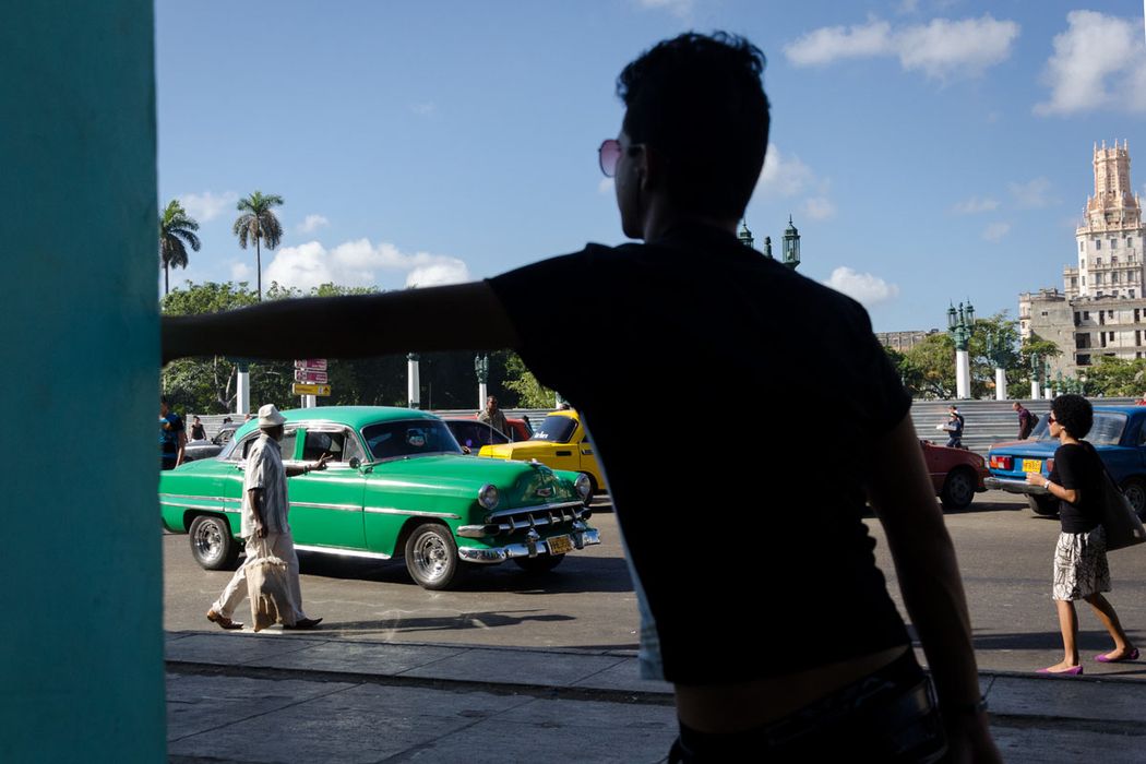 young cuban man and an old green car in havana
