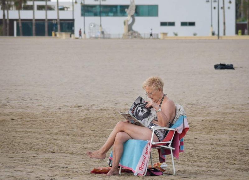 lonely woman reading in the valencia urban beach by louis alarcon