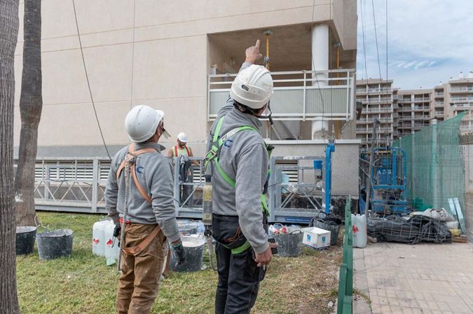 2 trabajadores de grupo CGC están revisando la restauración de una fachada en Valencia