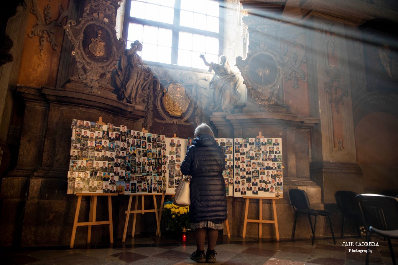 Una mujer reza en una iglesia en el centro de Lviv, frente a las fotografías de combatientes que están luchando contra la invasión Rusa a Ucrania. Marzo 2022. 