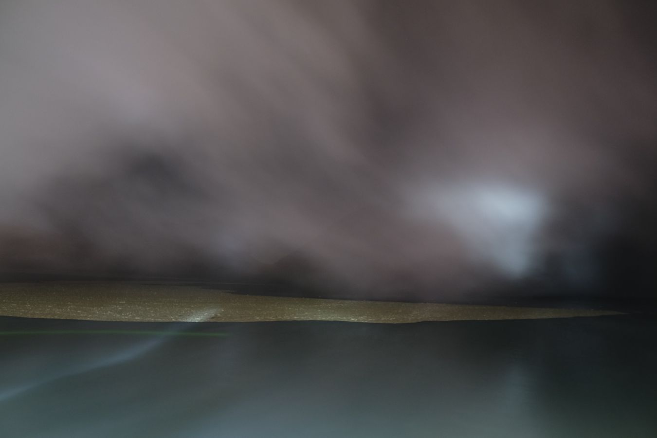 Acid particles in the lake, partially covered by smoke in the crater of the Ijen volcano at night