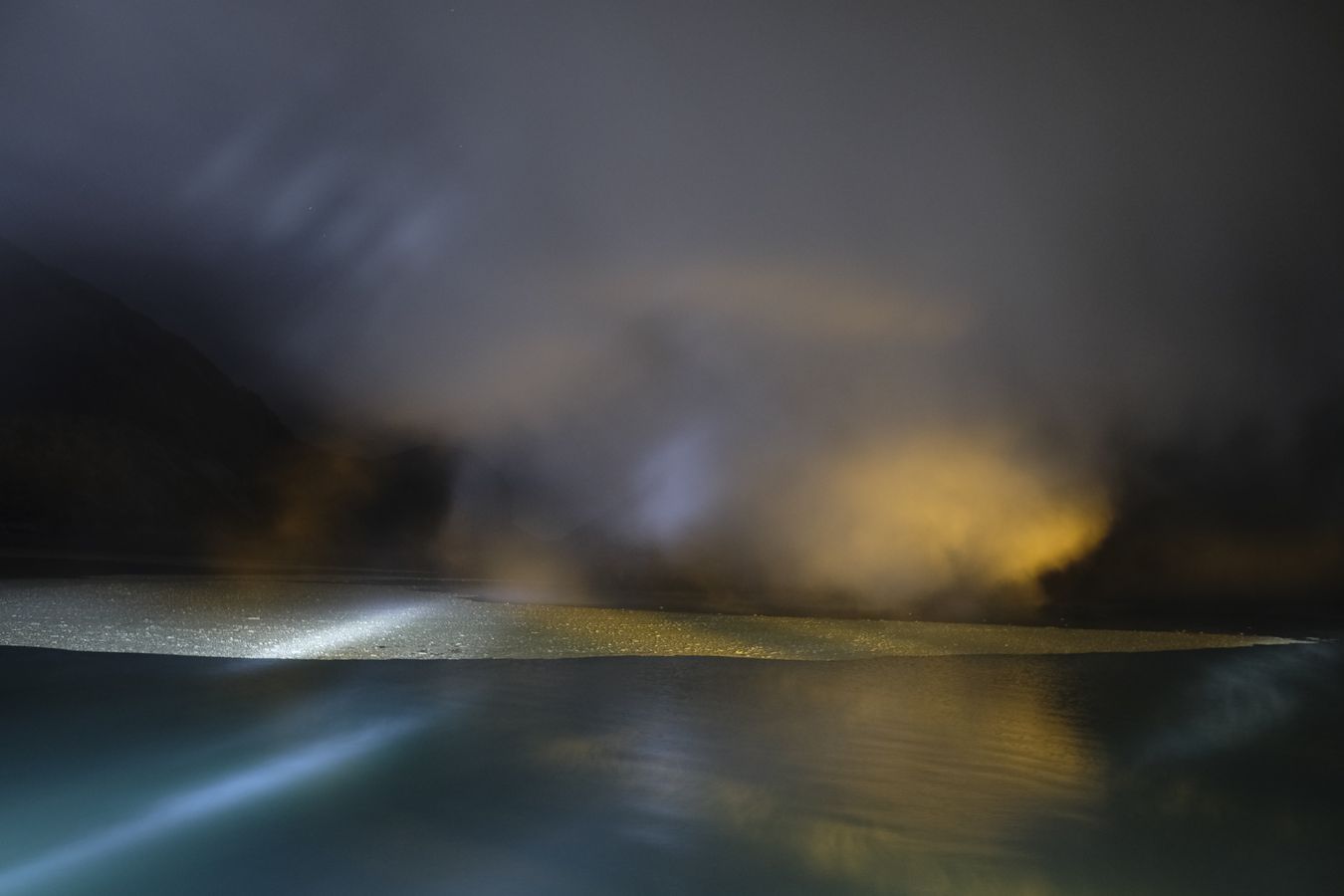 Acid particles in the lake, partially covered by smoke in the crater of the Ijen volcano at night