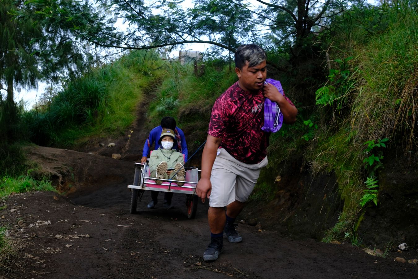 Porters push a wheelbarrow with a tourist on their way to the top of Ijen volcano