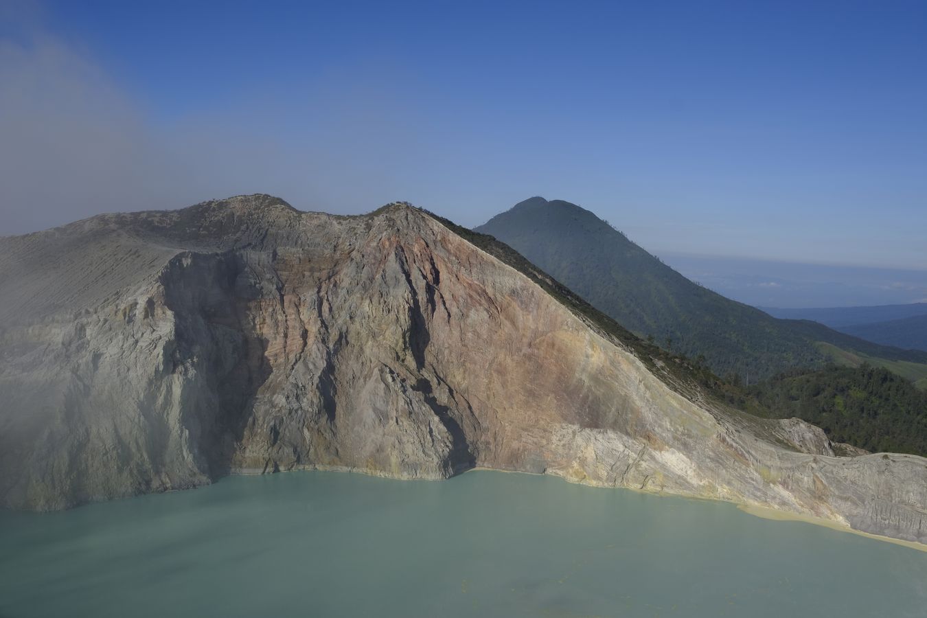 Views of the lake in the caldera of the Ijen volcano and other volcanic cone behind it 