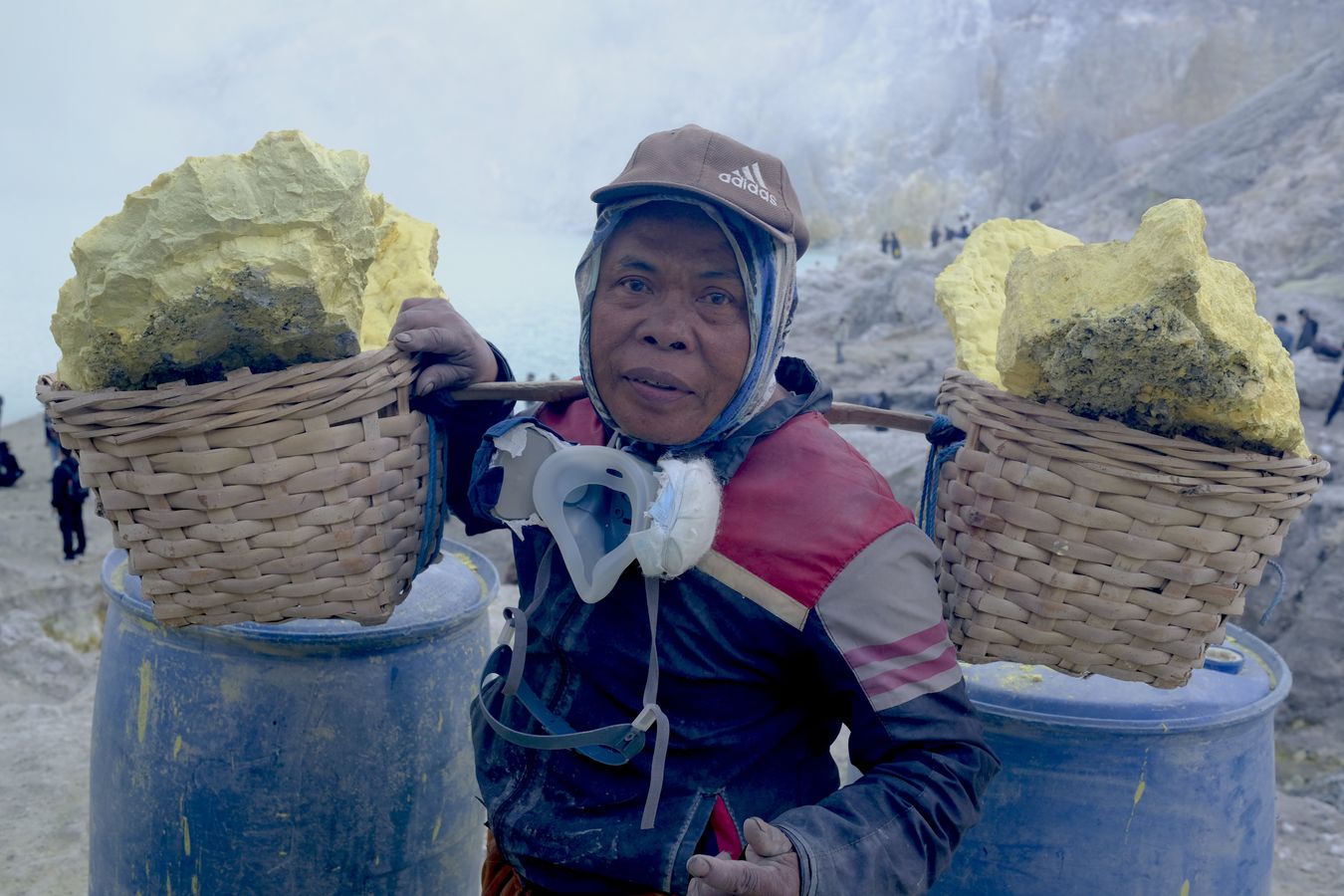 A miner carries traditional basket filled with sulfur stones