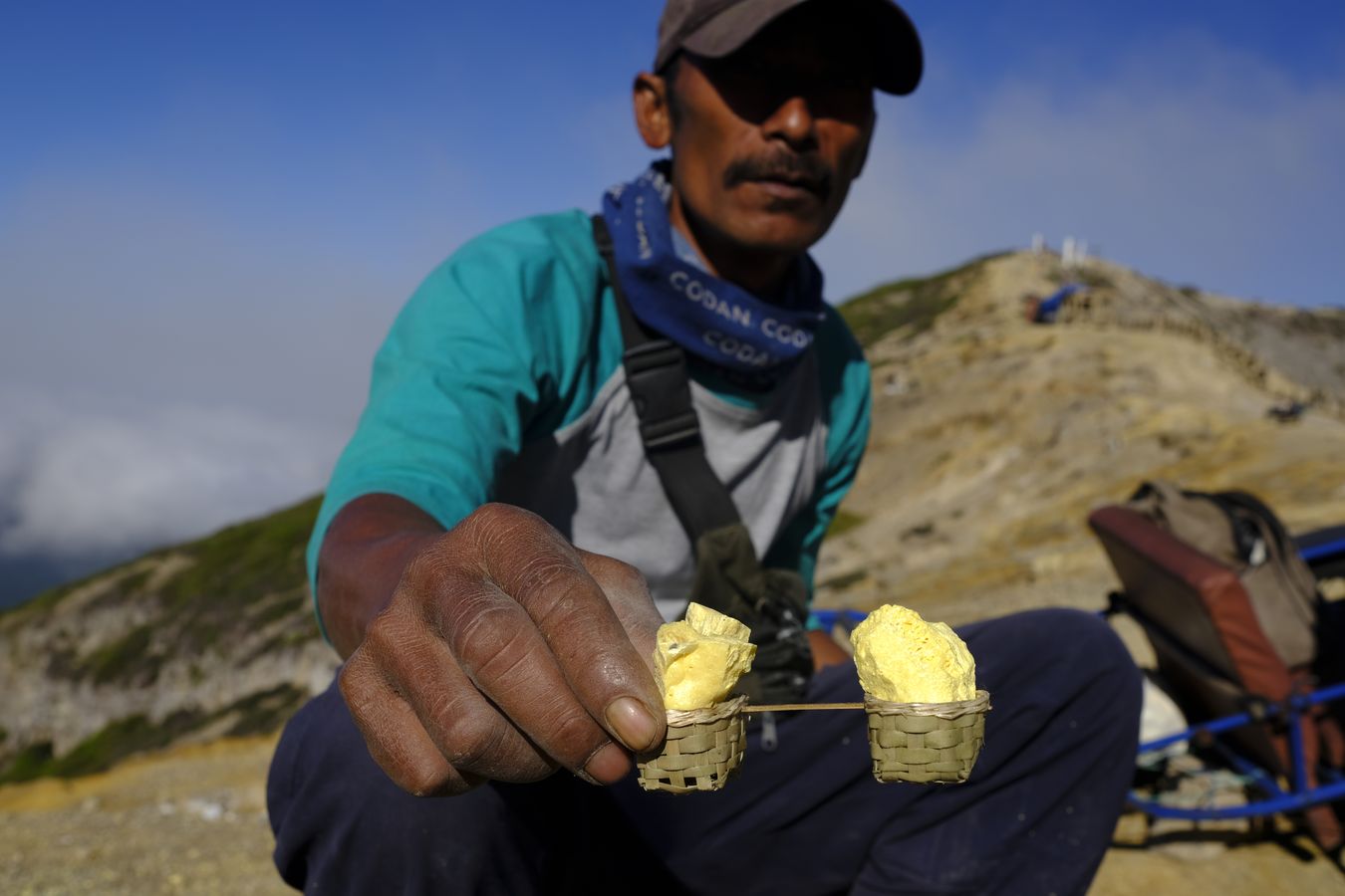 Miner shows a miniature of the traditional basket for carrying sulfur, created as a souvenir to sell to tourists