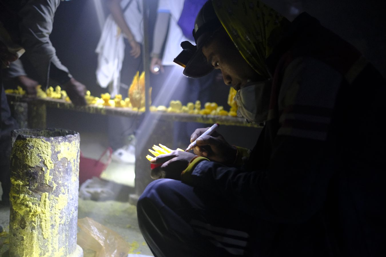 Miner carves a piece of sulfur to sell to tourists as a souvenir