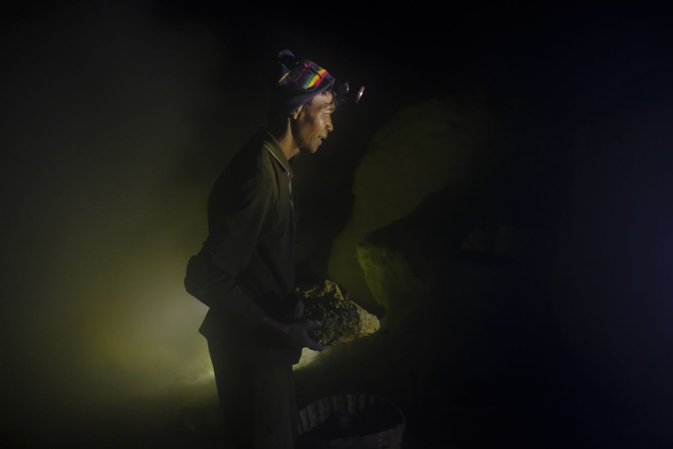 Miner extracting sulfur at night in the crater of the Ijen volcano