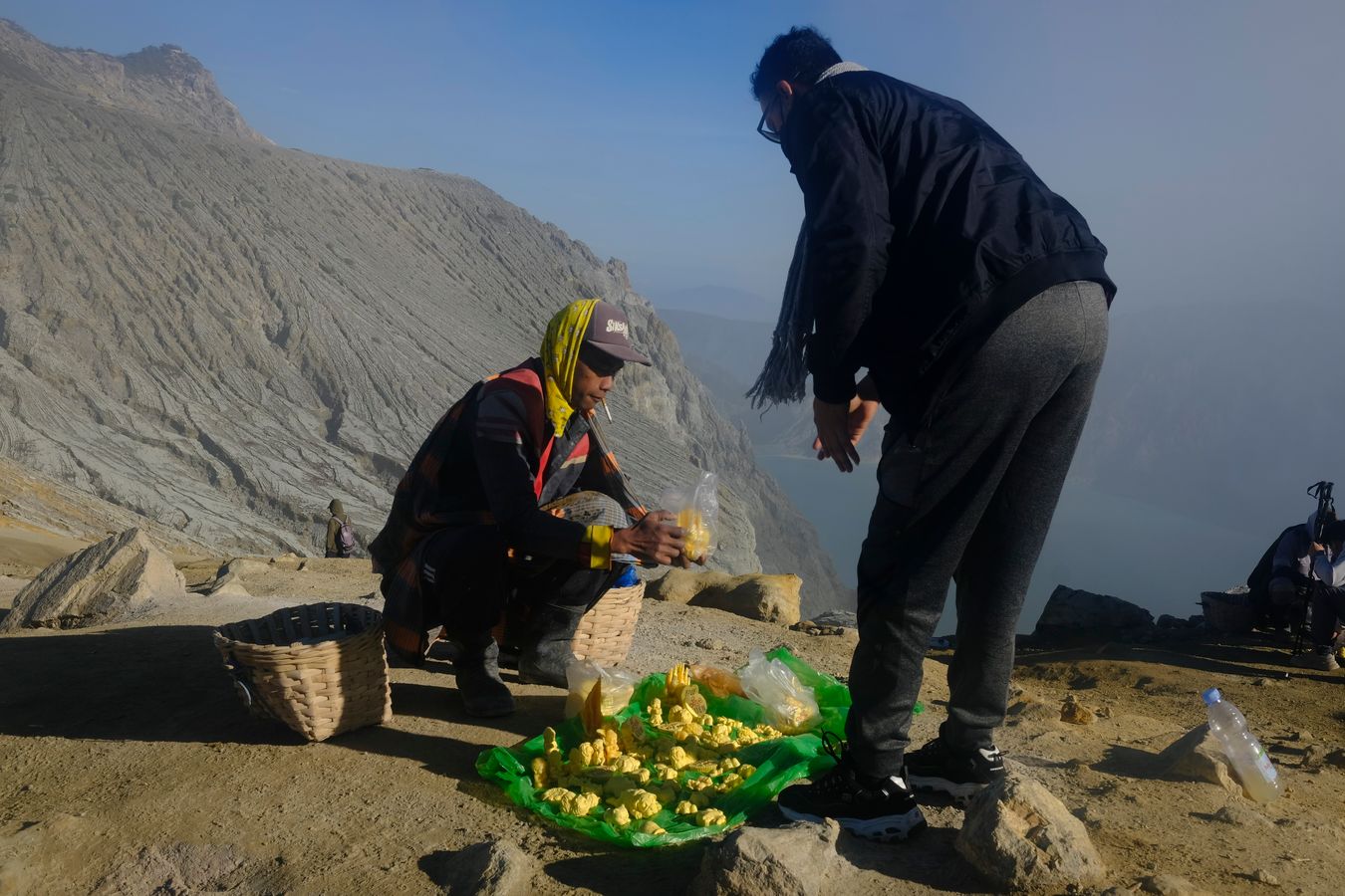 Miner sells small carving made of sulfur as a souvenir to a tourist 