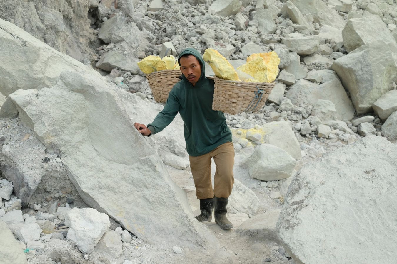 Miner ascending from the crater of the Ijen volcano with traditional baskets loaded with sulfur