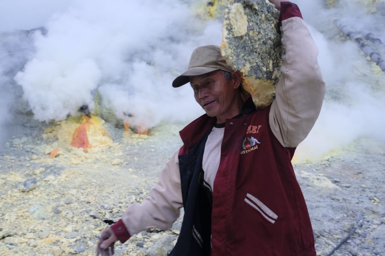 Miner carries a large stone of sulfur mined in the crater of the Ijen volcano