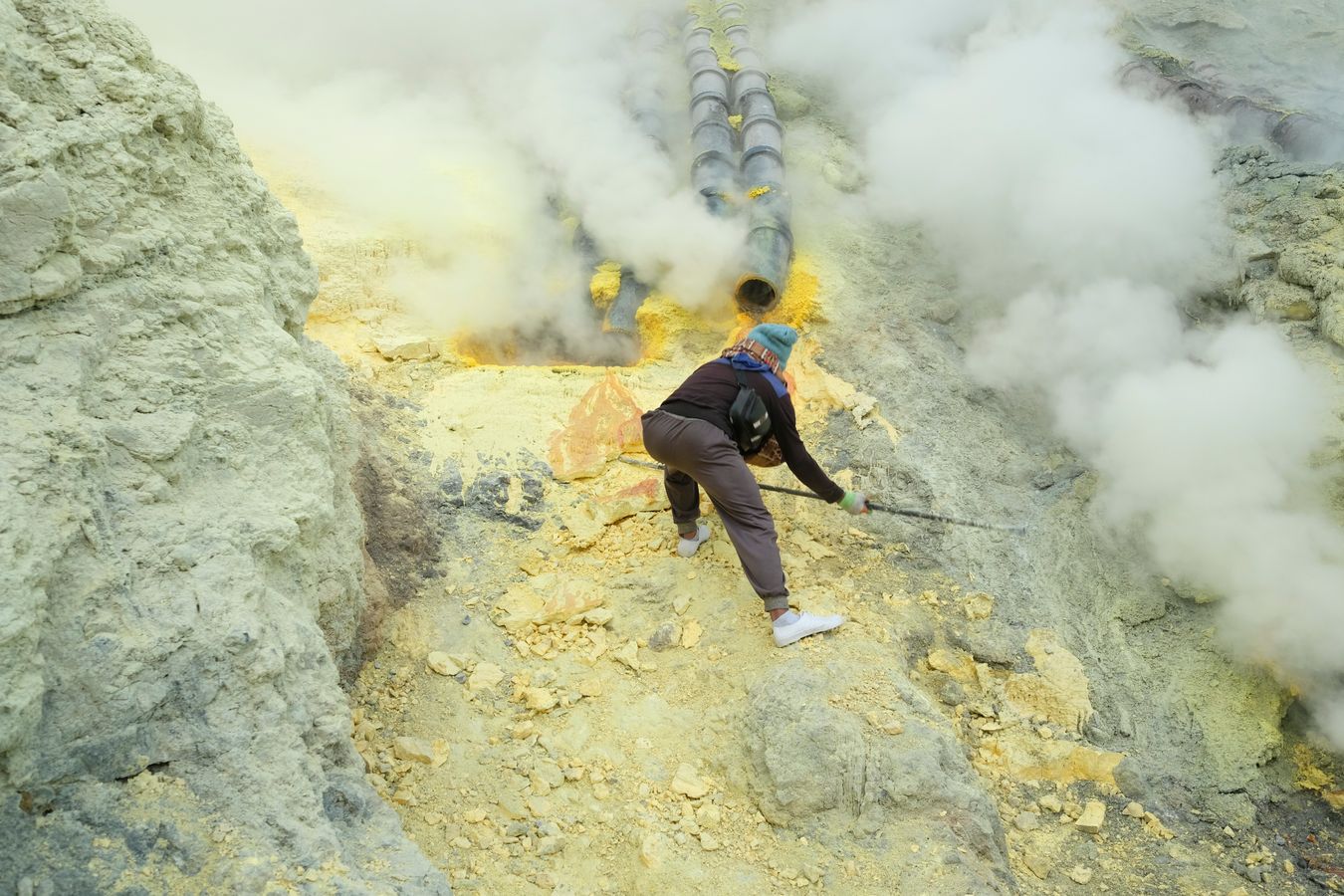 Miner extracts large blocks of sulfur from the crater of the Ijen volcano with the only help of a steel bar