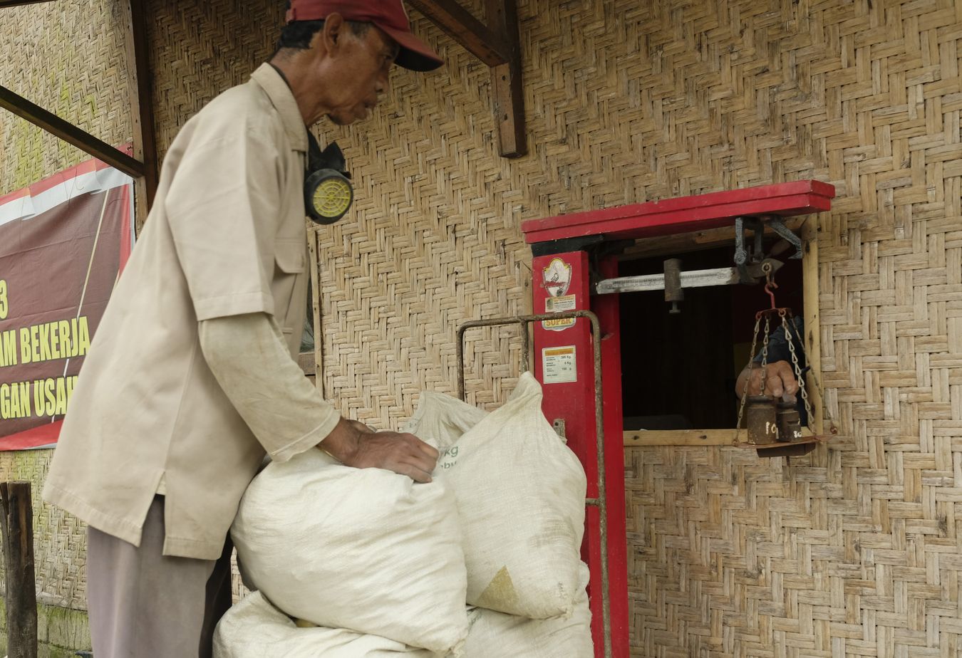 Miner watches the weighing of sulfur extracted from the crater of the Ijen volcano the night before