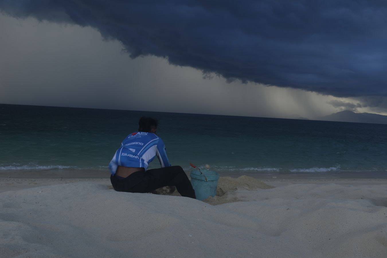 Ranger collects green turtle eggs on a stormy sunset.