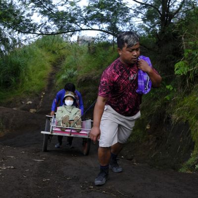 Porters push a wheelbarrow with a tourist on their way to the top of Ijen volcano