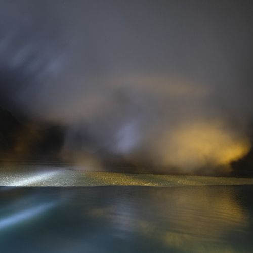 Acid particles in the lake, partially covered by smoke in the crater of the Ijen volcano at night