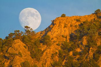 Rising full moon at sunset over puig de sa Galera, Tramuntana mountains, Majorca