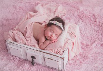 niña recien nacida en cajon blanco y fondo rosa