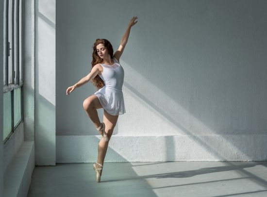 Bailarina de clasico con pose y vestido blanco con luz  natural entrando por al ventana