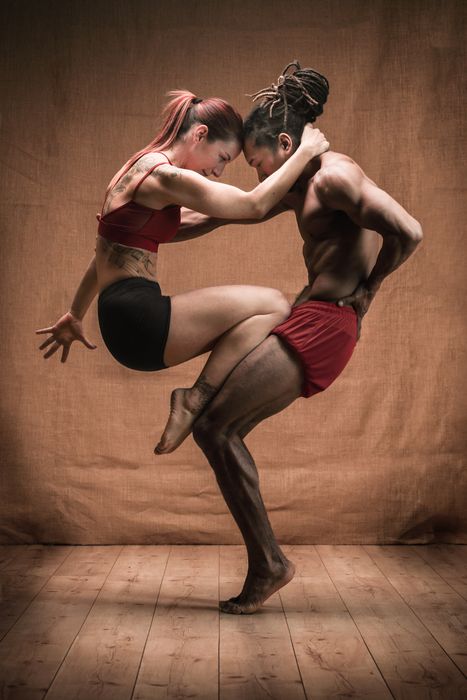 Bailarines en acrobacia dibujando un corazón con sus cuerpos. En colores cálidos. Tensión en sus cuerpos. Hombre y mujer.