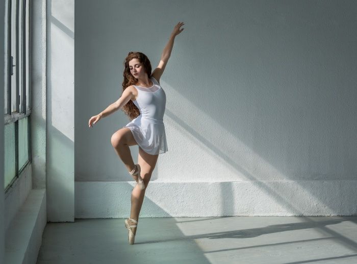 Bailarina de clasico con pose y vestido blanco con luz  natural entrando por al ventana