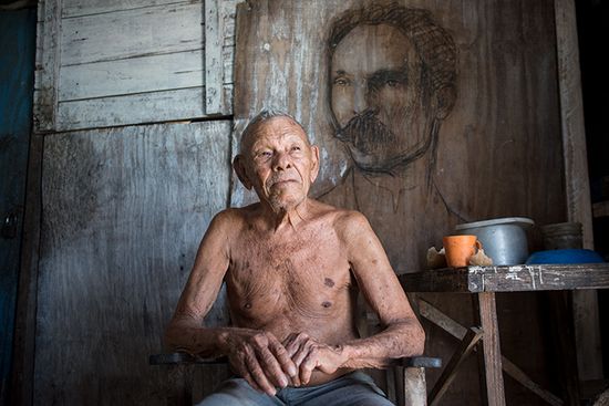 old cuban man with a graffiti of jose marti behind him
