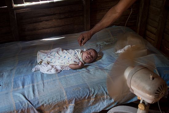 little baby in a bed in front of a fan , anthropological photo of cuba