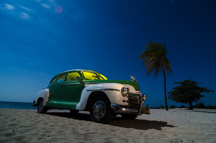 old cars at night in cuba by louis alarcon
