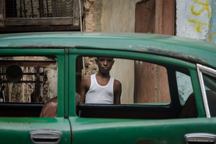 young cuban boy in a car window,  street photography in cuba