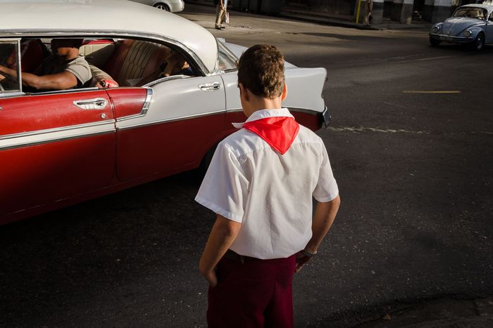 cuban student and old car in havana´s street,  street photography in cuba