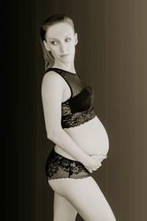 Mujer embarazada sobre fondo negro en lenceria
