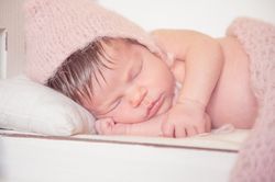 bebe dormida en cuna con gorro rosa