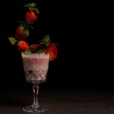 copa cristal batido fresa fresas en el aire hierbabuena fondo negro strawbeiies