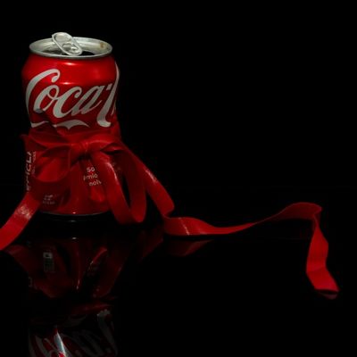 lata de coca-cola con una cinta roja sobre fondo negro