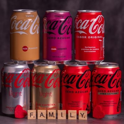 Torre de varias latas de coca-cola de distintos modelos con la palabra familia 