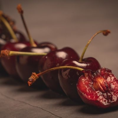 fila de cerezas sobre fondo oscuro cereza mordida