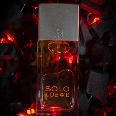 Frasco de perfume colonia Solo De Loewe sobre cama de brasa y fuego