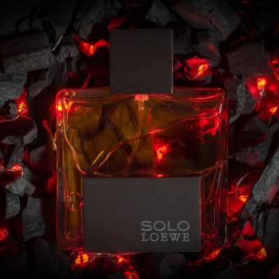 Frasco de perfume colonia Solo De Loewe sobre cama de brasa y fuego