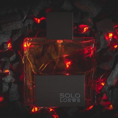 Frasco de perfume colonia Solo De Loewe sobre cama de brasa y fuego