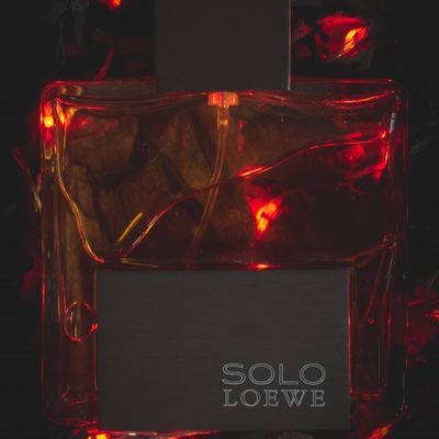 Frasco de perfume colonia Solo De Loewe sobre cama de brasa y fuego