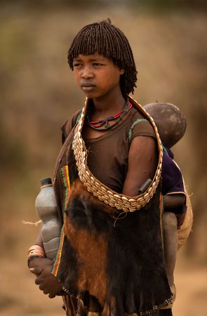 Mujer de la tribu Hamer con su hijo. vestida con pieles. Valle del Omo. Etiopia