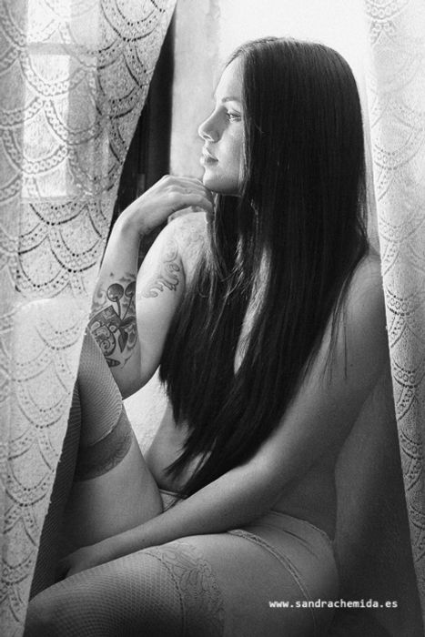 Mujer  en pose sexy sentada mirando a traves de la ventana
