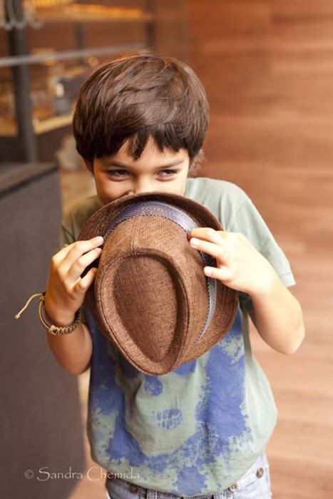 niño pequeño escondido tras un sombrero y riendose